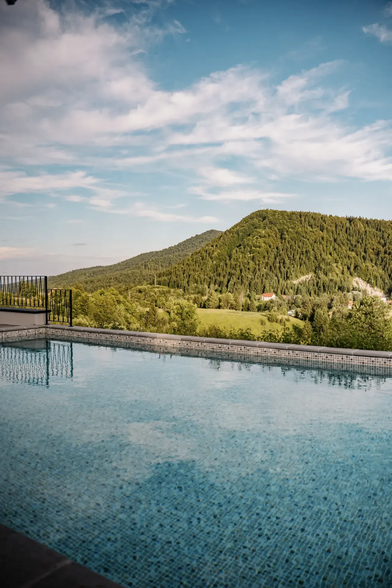 The heated pool's edge meeting the forested hills of Gorski kotar