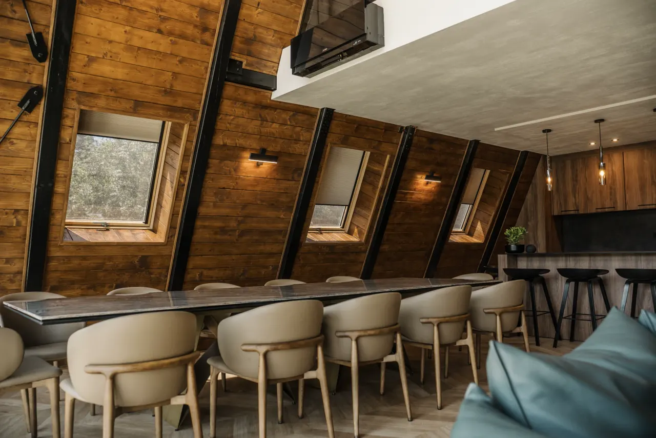 Long dining table beside the timber kitchen under warm pendant lighting