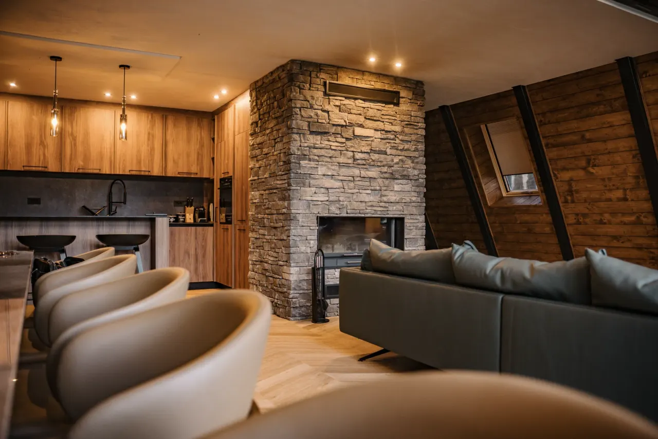 Living area with a stone fireplace and green leather sofas