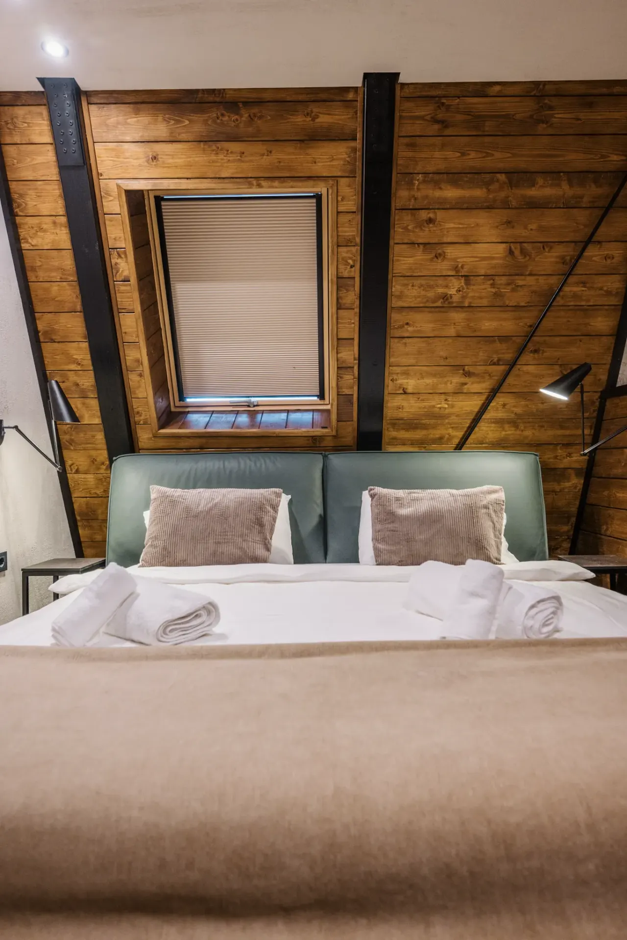 Bedroom with an upholstered green headboard and warm wood cladding