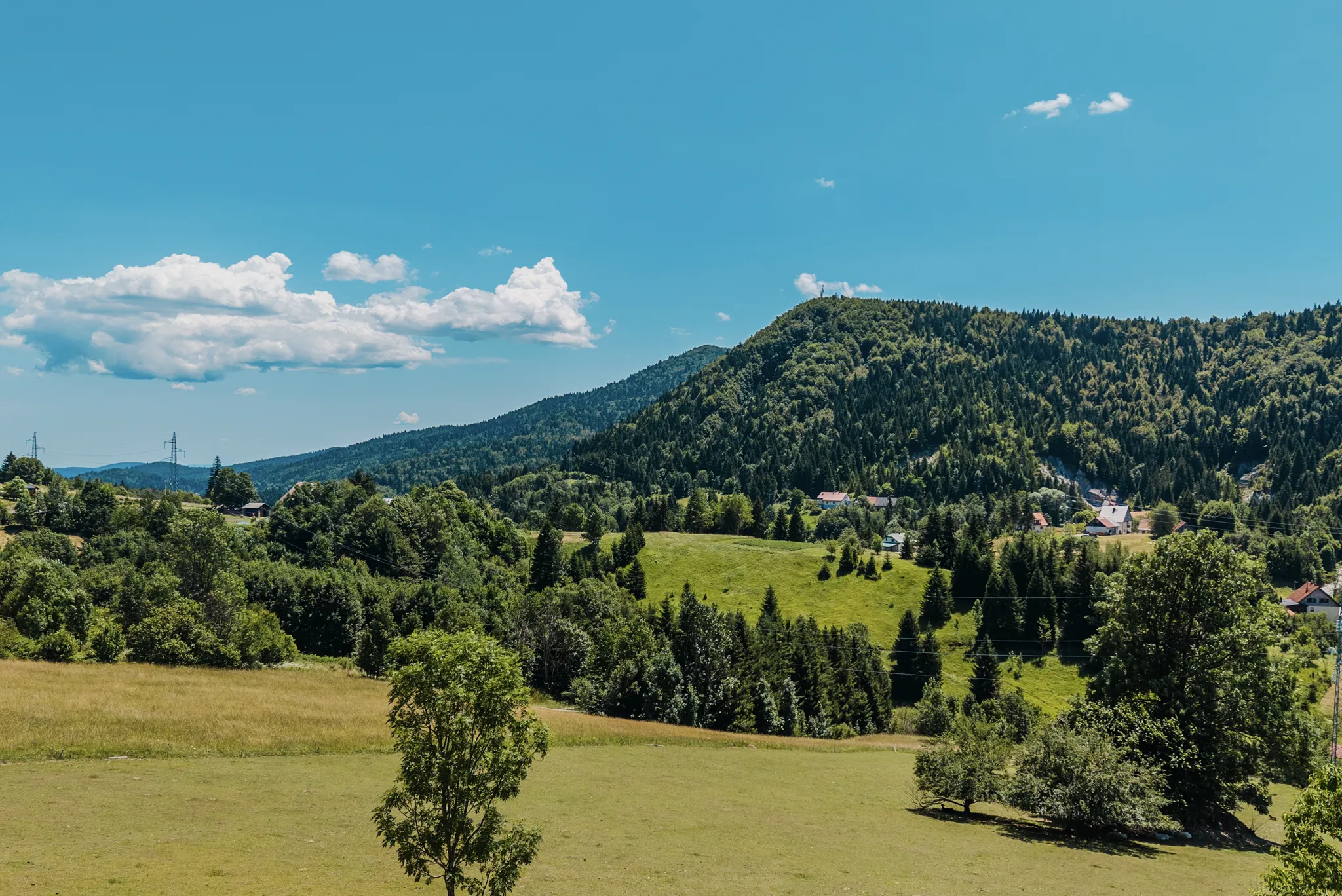 Pogled iz zraka na pošumljeni greben Ravne Gore u Gorskom kotaru, krošnje se pružaju do horizonta, a The Frame stoji na najvišem dijelu